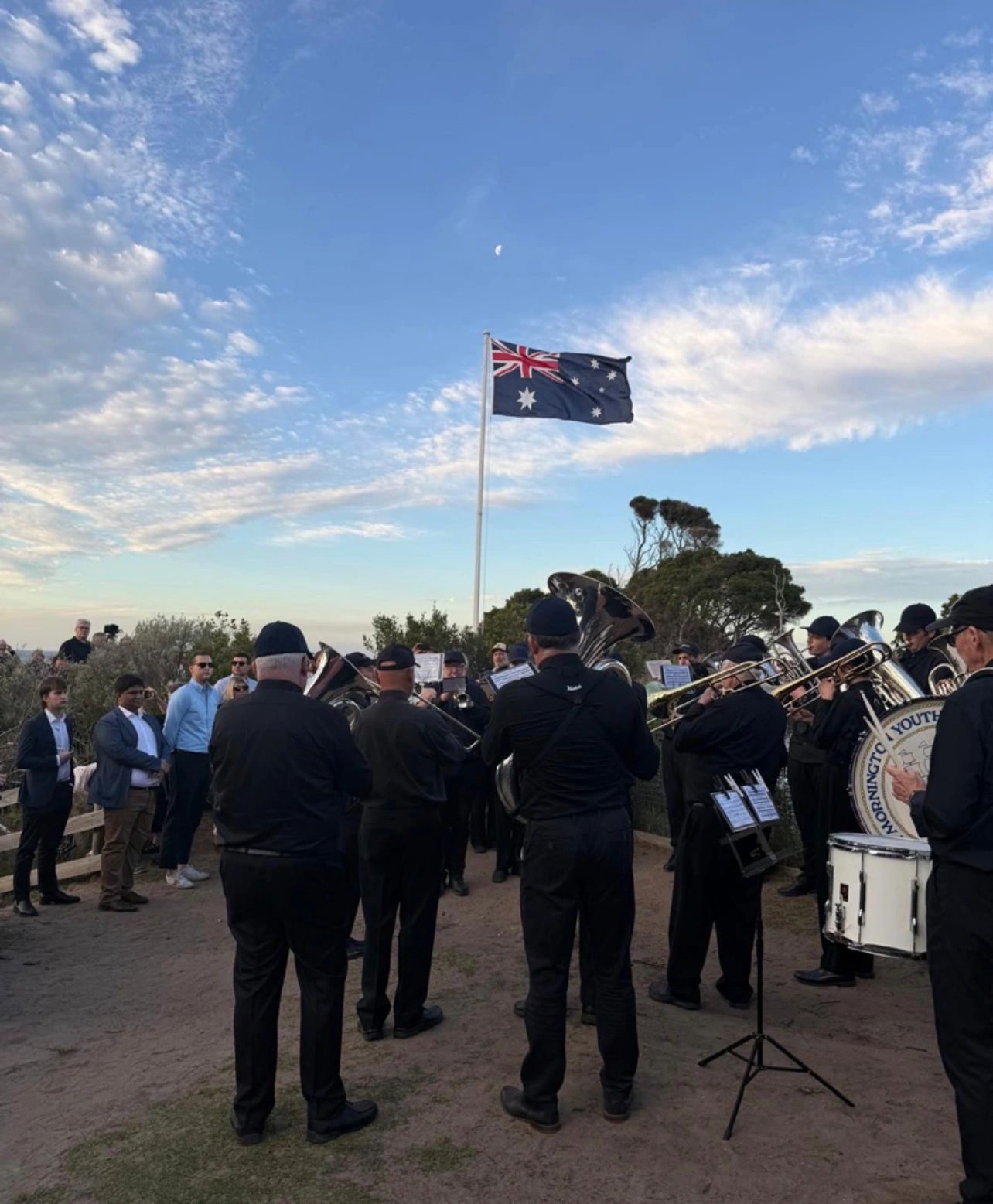 Brass band performing under the Australian flag at an outdoor remembrance ceremony