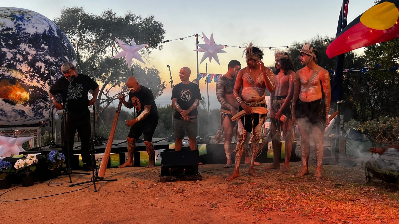 Cultural performers with didgeridoo and body paint at a dusk ceremony