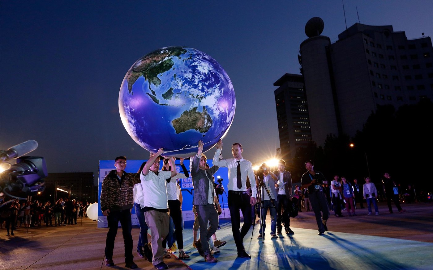 Visitors gathered beneath an illuminated Earth sphere at night