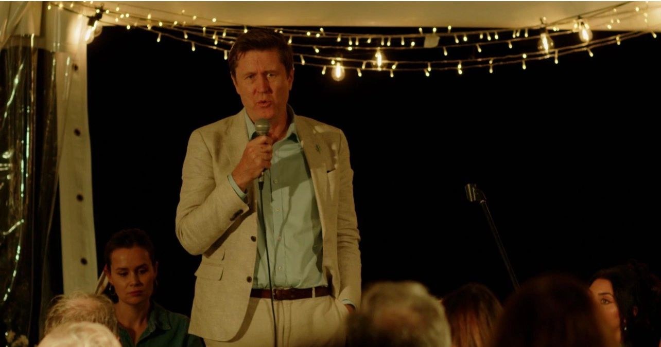 Guest speaker addressing an evening Sunset Garden Talk under festoon lights